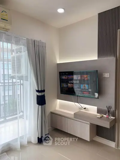 Modern living room with wall-mounted TV and balcony view in stylish apartment.
