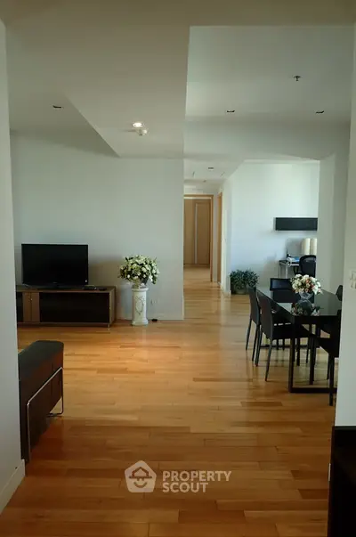 Spacious modern living room with hardwood floors and elegant dining area in open layout apartment.