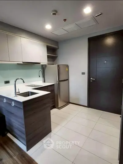 Modern compact kitchen with sleek cabinets and stainless steel fridge