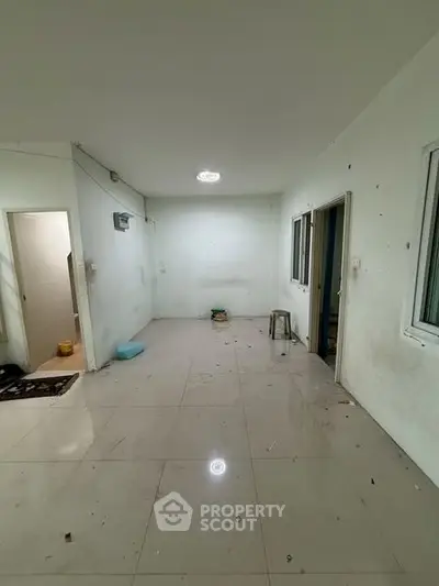 Spacious empty room with tiled flooring and white walls, ready for customization.
