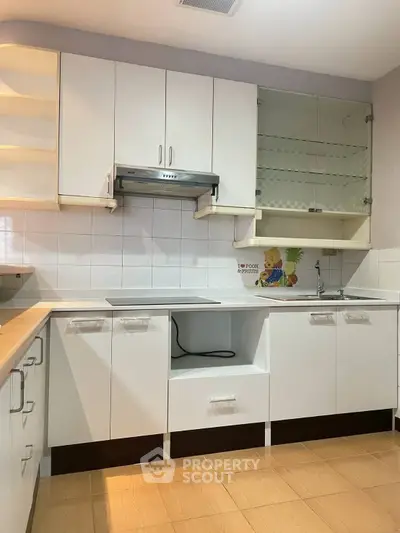 Modern kitchen with sleek white cabinets and wooden flooring, featuring a glass cabinet and efficient layout.