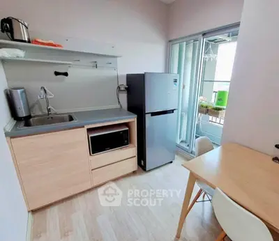Modern compact kitchen with fridge, microwave, and balcony access