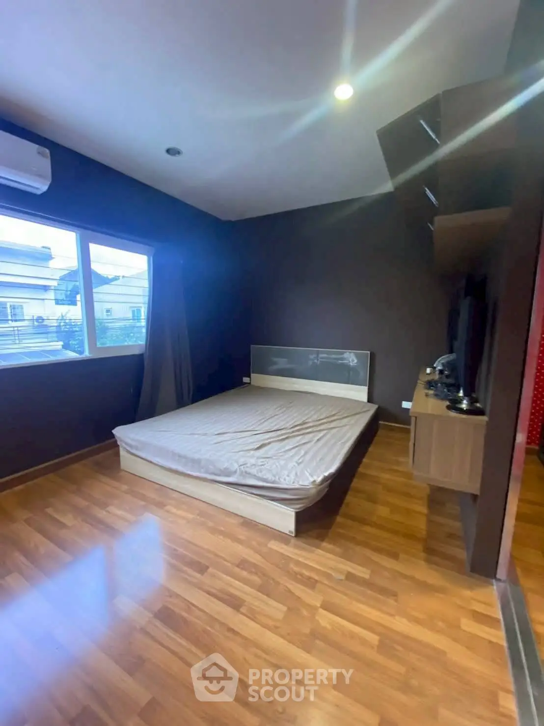 Spacious bedroom with wooden flooring and large window for natural light