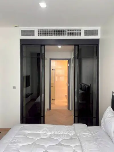 Modern bedroom with glass sliding doors leading to a sleek bathroom