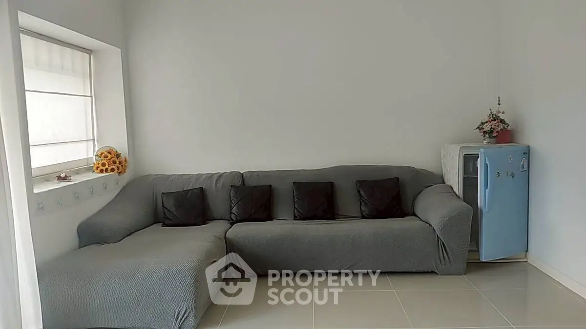 Cozy living room with gray sofa and mini fridge, perfect for relaxation.