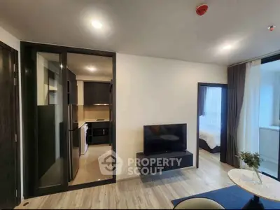 Modern apartment interior with open living room and kitchen, featuring sleek design and cozy bedroom.