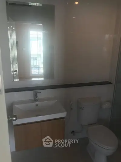 Modern bathroom with sleek fixtures and large mirror in a contemporary home.