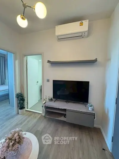 Modern living room with air conditioning and stylish decor, featuring a TV and elegant lighting.