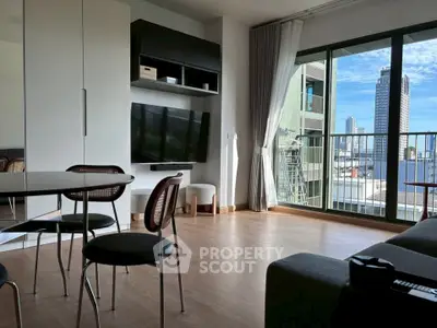 Modern living room with balcony and city view, featuring sleek furniture and natural light.