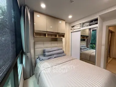 Cozy bedroom with large window and modern built-in storage in a stylish apartment.
