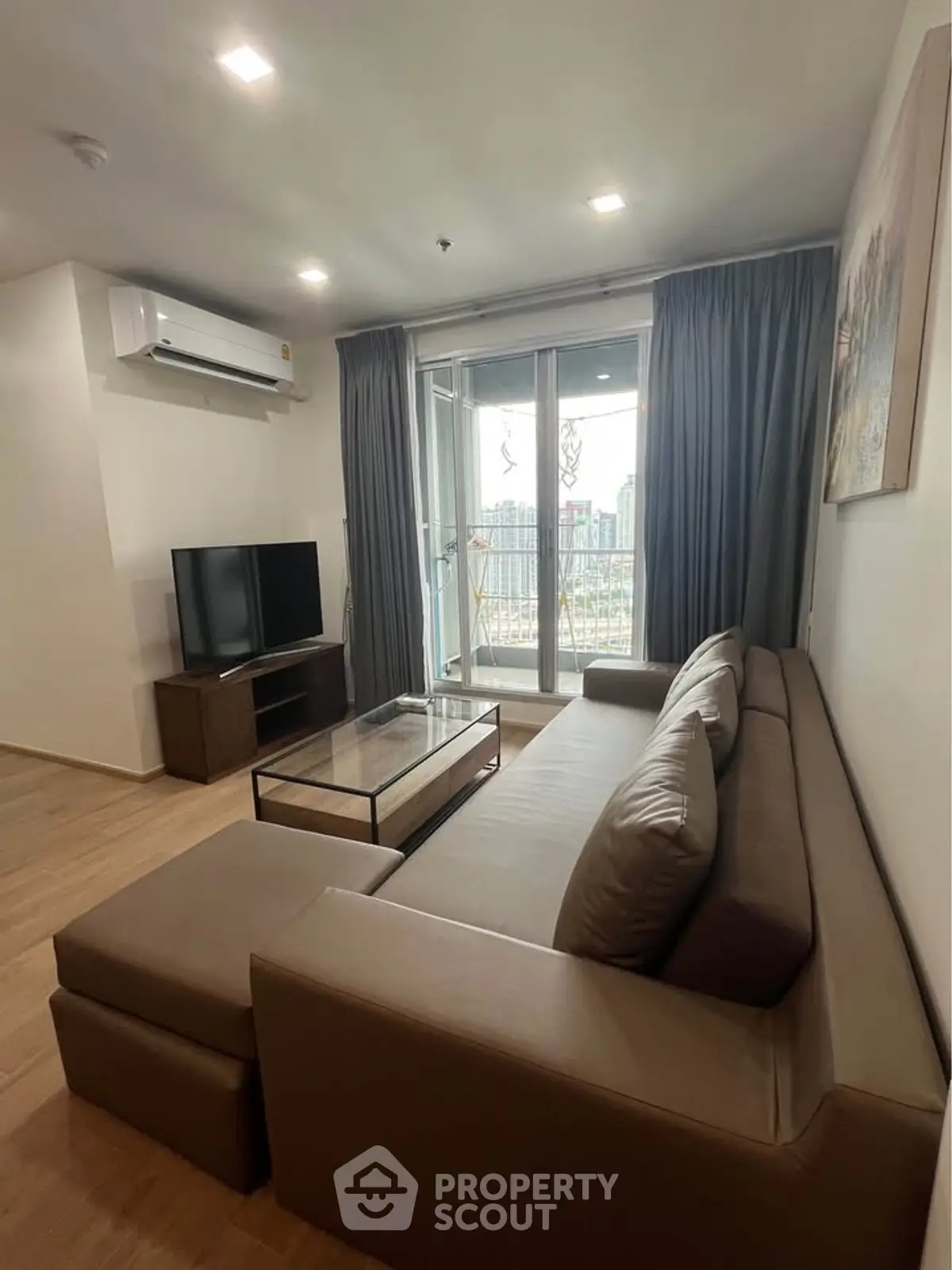 Modern living room with large sofa and city view balcony