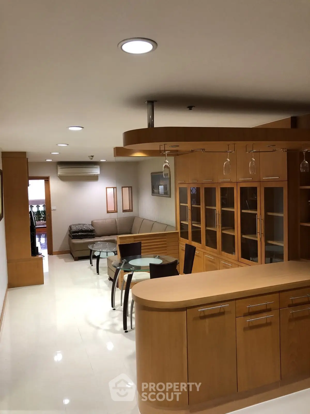 Spacious living room with modern wooden cabinetry and elegant glass dining table.