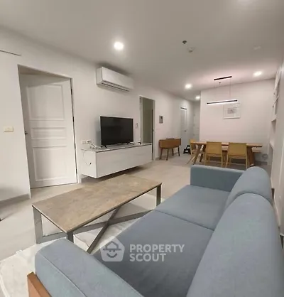 Modern living room with sleek furniture and open layout, featuring a stylish sofa and dining area.