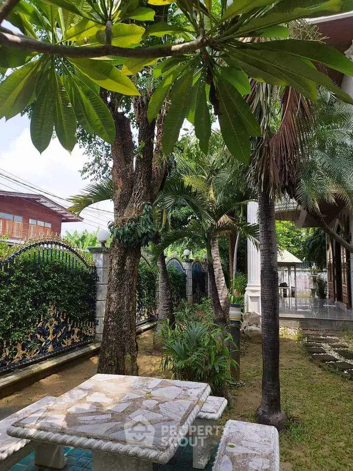 Charming garden with stone seating under lush trees, perfect for relaxation and outdoor gatherings.