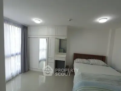 Bright bedroom with large window and built-in wardrobe in modern apartment.