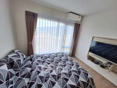 Cozy bedroom with modern decor and large window offering natural light.