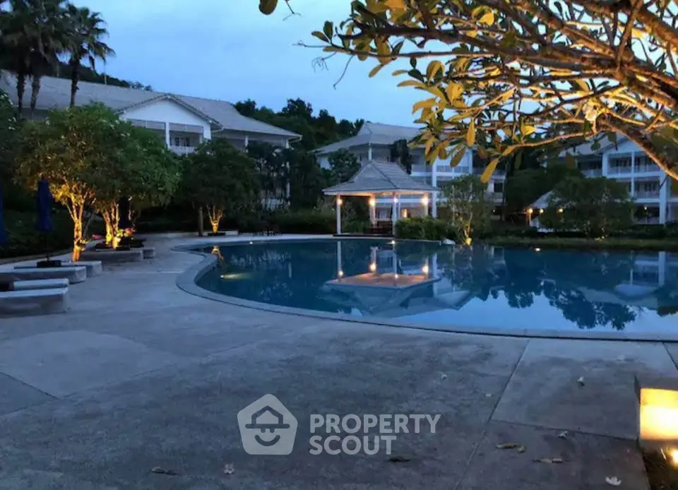 Luxurious resort-style pool area with ambient lighting and lush greenery, perfect for relaxation and leisure.