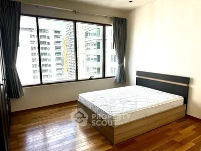 Spacious bedroom with large window offering city views in modern apartment.