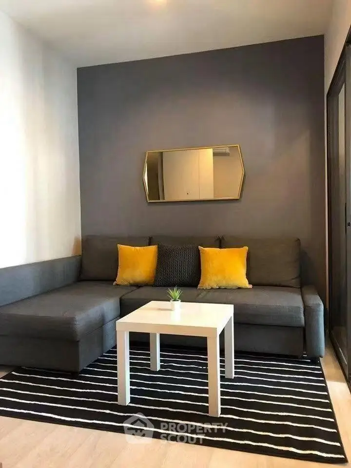 Modern living room with stylish gray sofa, yellow cushions, and chic decor.