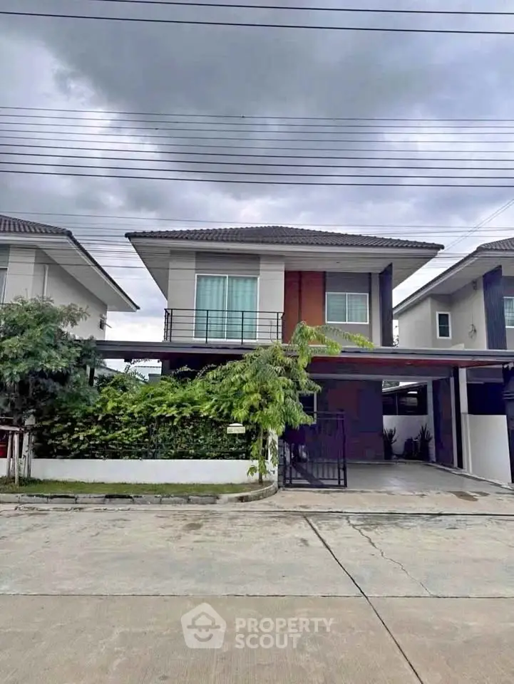Modern two-story house with balcony and driveway in a suburban neighborhood.