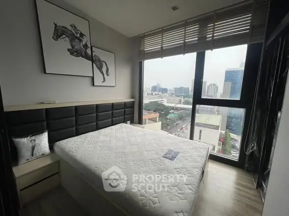 Modern bedroom with city view, featuring stylish decor and large windows for natural light.