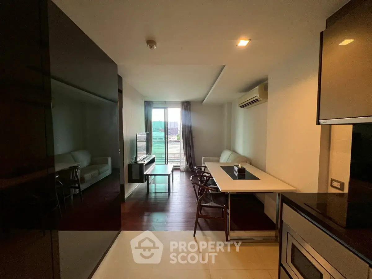Modern living room with sleek furniture and large window offering natural light and city view.