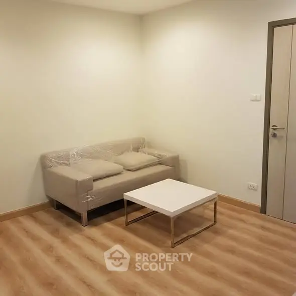 Minimalist living room with modern sofa and coffee table on wooden flooring.