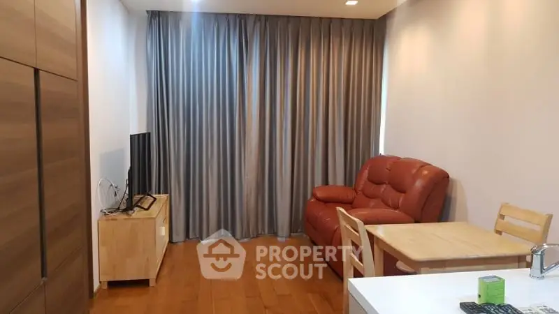 Cozy living room with wooden flooring, red leather sofa, and modern TV setup.