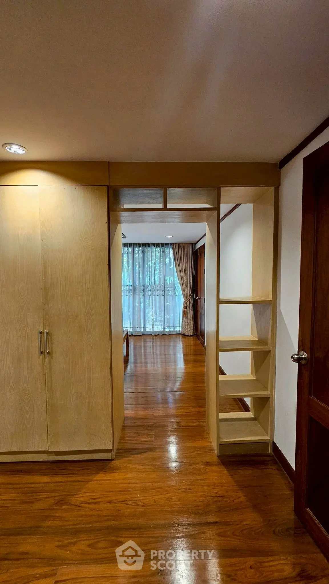 Spacious bedroom with wooden flooring and built-in wardrobe, featuring large windows for natural light.