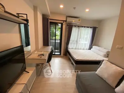 Modern studio apartment with cozy bed, desk, and balcony view.