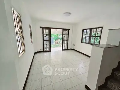 Spacious living room with tiled floor and garden view through large windows.