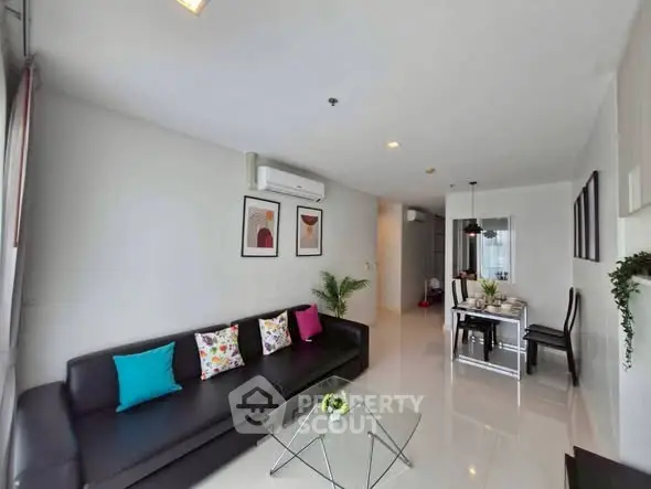 Modern living room with sleek black sofa and vibrant cushions in a stylish apartment.
