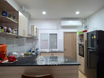 Modern kitchen with sleek cabinets and appliances, featuring a black marble countertop and ample storage space.