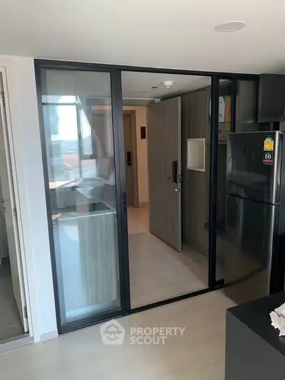 Modern kitchen with sleek design and glass sliding doors in a contemporary apartment.