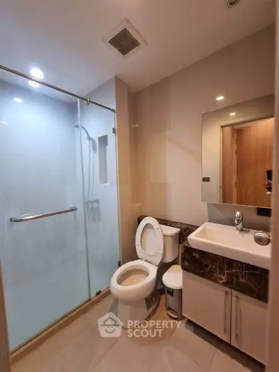 Modern bathroom with glass shower and sleek vanity in contemporary apartment.
