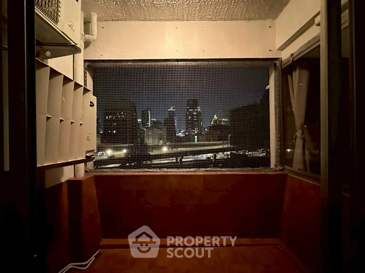 Cozy balcony with city skyline view at night, perfect for relaxation.
