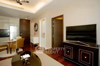 Modern living room with elegant furniture and open kitchen layout, featuring a sleek TV setup and stylish decor.