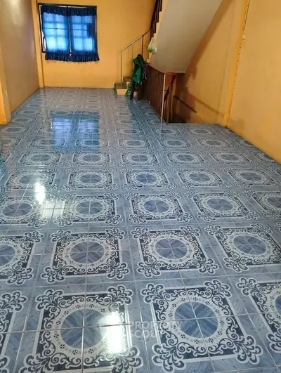 Spacious room with unique blue patterned tile flooring and a window with blue curtains.