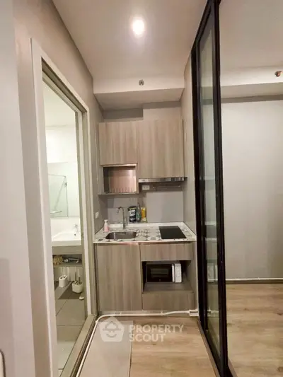 Compact modern kitchen with sleek cabinetry and integrated appliances in a stylish apartment.