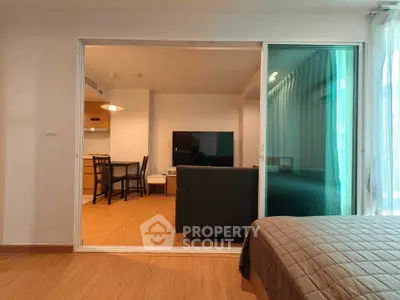 Modern open-plan living room with cozy seating and dining area, featuring sleek wooden flooring and ambient lighting.