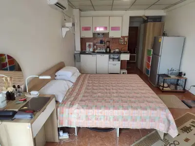 Cozy studio apartment with integrated kitchen and bedroom, featuring modern appliances and tiled flooring.