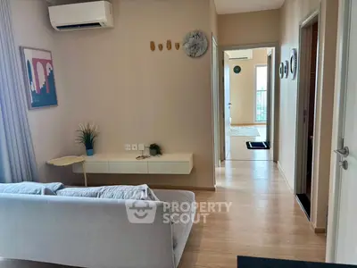 Modern living room with stylish decor and air conditioning, featuring a cozy sofa and wall art.