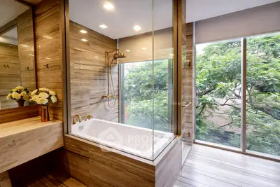 Luxurious bathroom with elegant bathtub and floor-to-ceiling windows offering serene tree views.