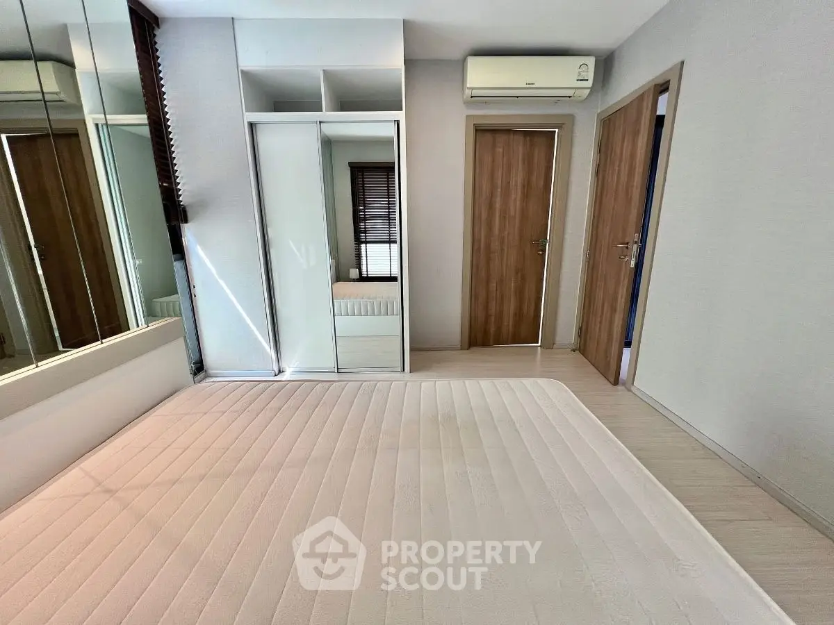 Modern bedroom with mirrored wardrobe and air conditioning unit
