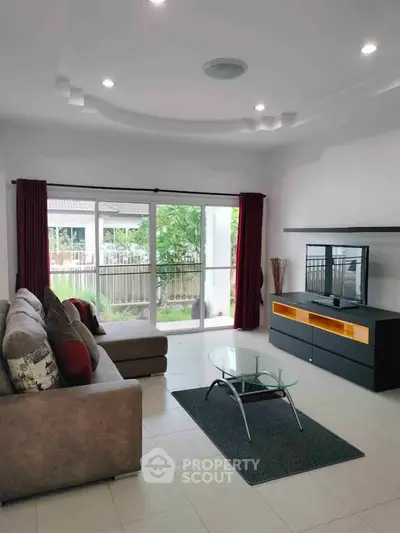 Spacious living room with modern decor and large glass doors leading to a garden view.