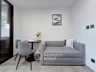 Modern living room with sleek gray sofa and dining area in contemporary apartment.
