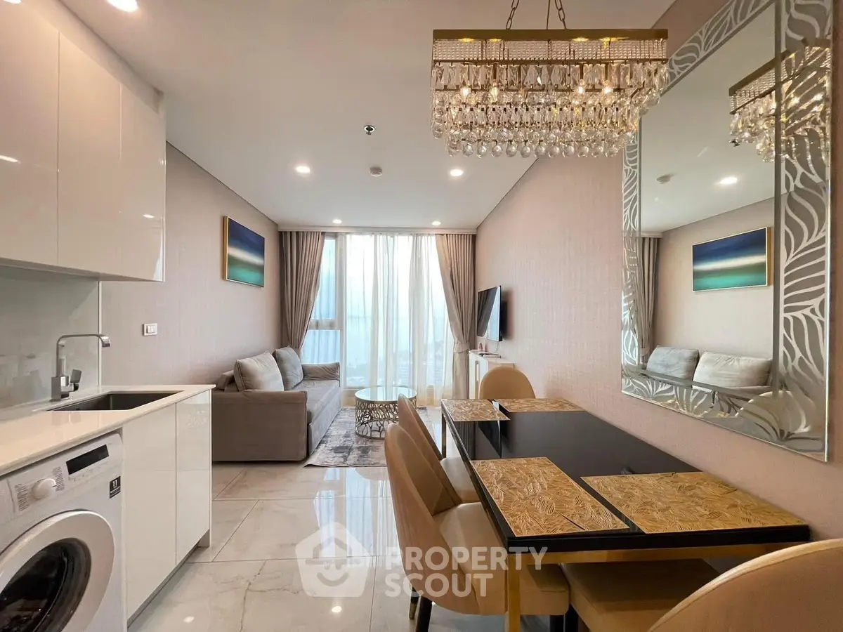 Luxurious modern living room with elegant chandelier and open kitchen layout.