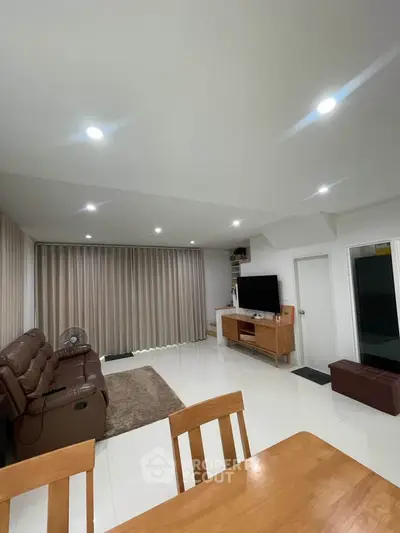 Spacious modern living room with leather sofa and entertainment center, perfect for relaxation.