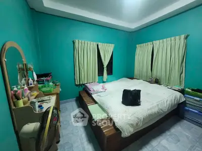 Cozy bedroom with teal walls, large bed, and vanity in a well-lit space.