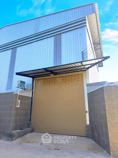 Modern industrial warehouse with large roller door and sleek metal exterior.